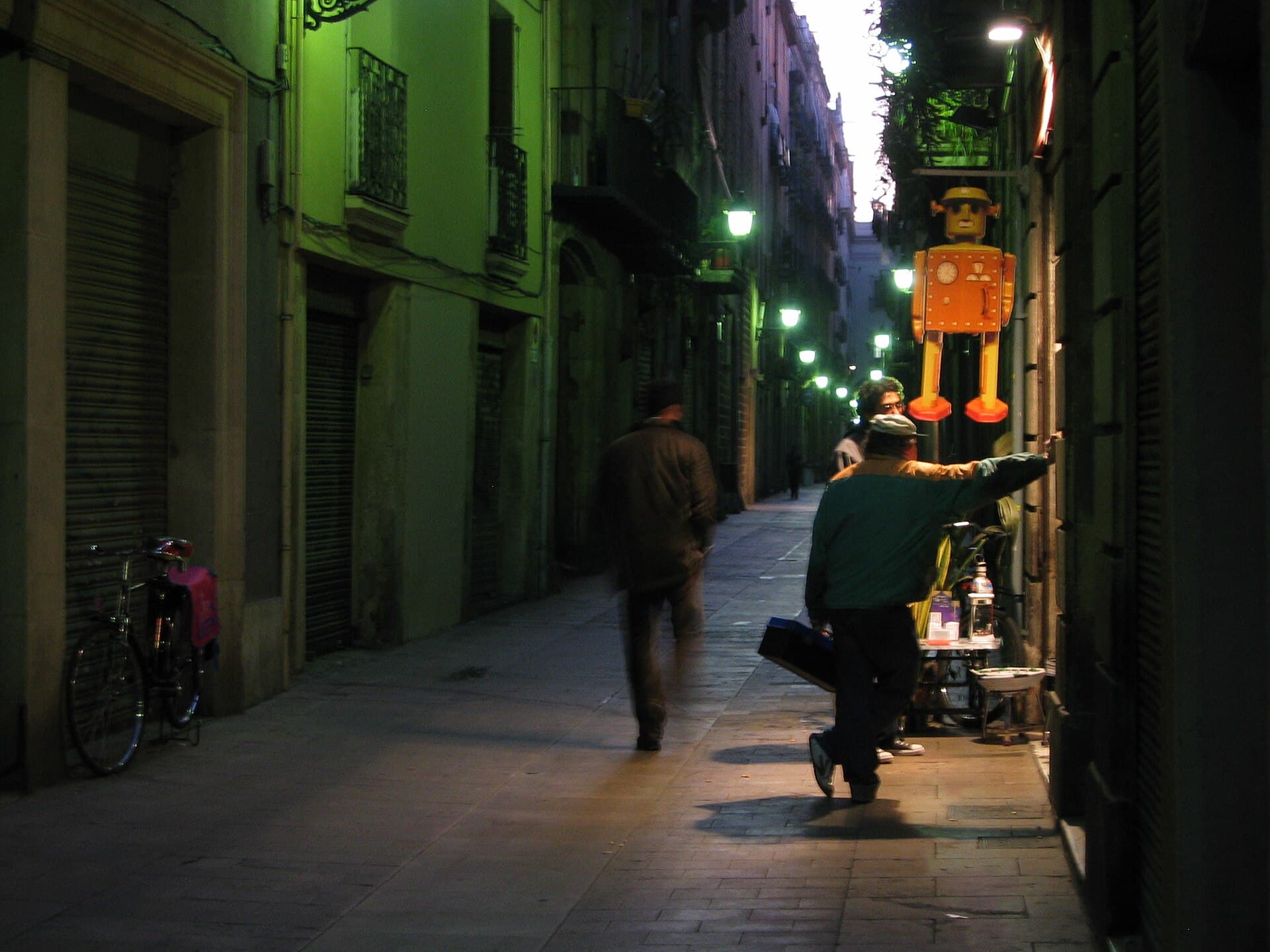 Ruelle pavée du Barri Gòtic de Barcelone la nuit, éclairée par des lanternes entre de hautes façades en pierre