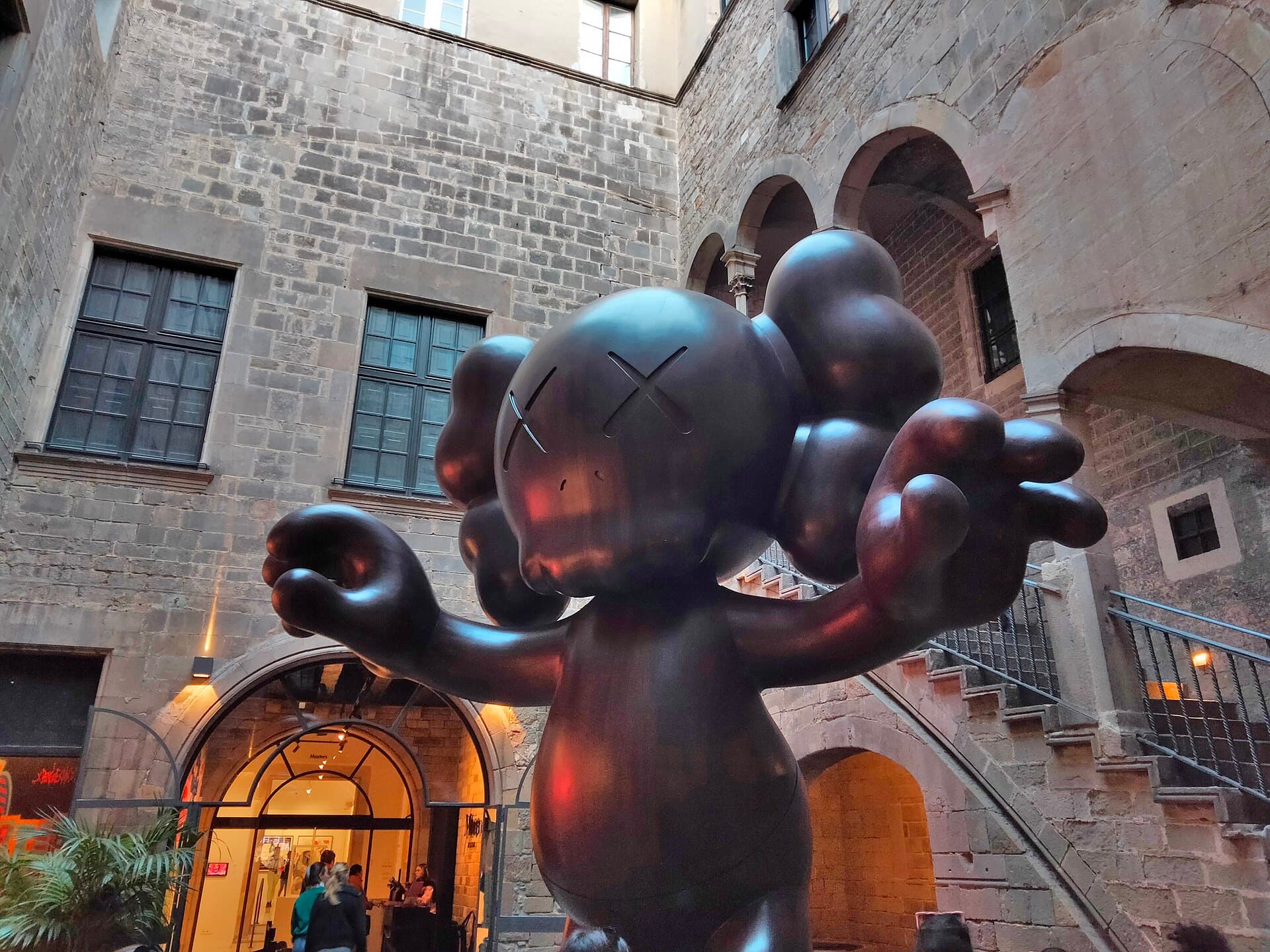 Grande sculpture sombre de KAWS dans le patio en pierre du Palau Cervelló, siège du Moco Museum, rue Montcada à Barcelone